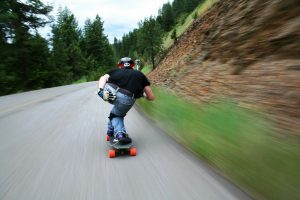 Man riding a longboard on a paved road.