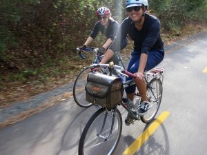 Two people bike commuting with bags on their bikes.