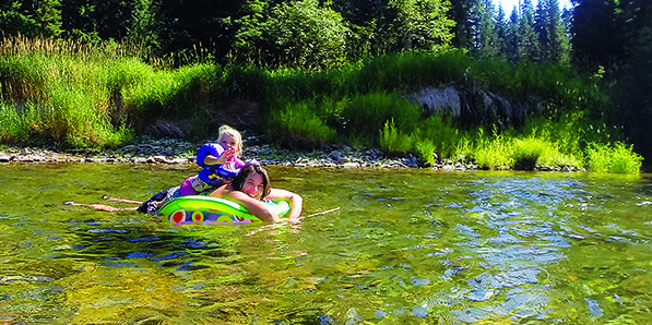 Mom and young daughter floating on a tube down the river.