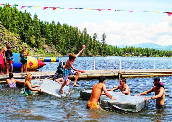 Campers playing in the water of Davis Lake and jumping off floating dock pads at Camp Spalding.