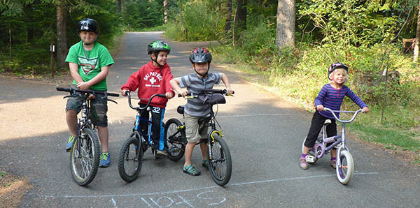 Three boys and girl on their bikes ready to ride the campground loop road.