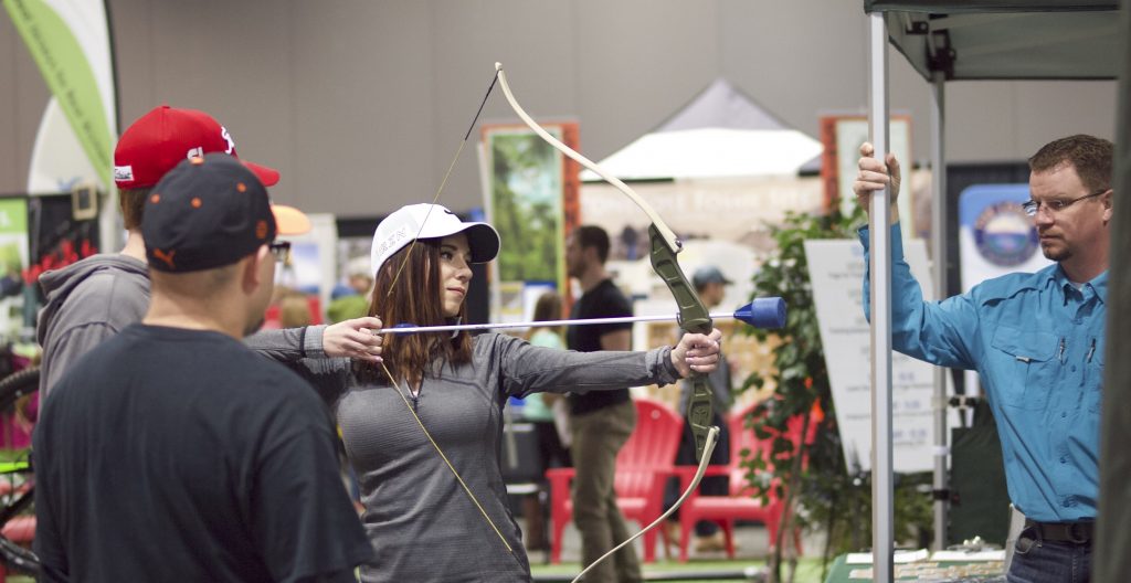 A woman tries her hand at archery at an Expo booth