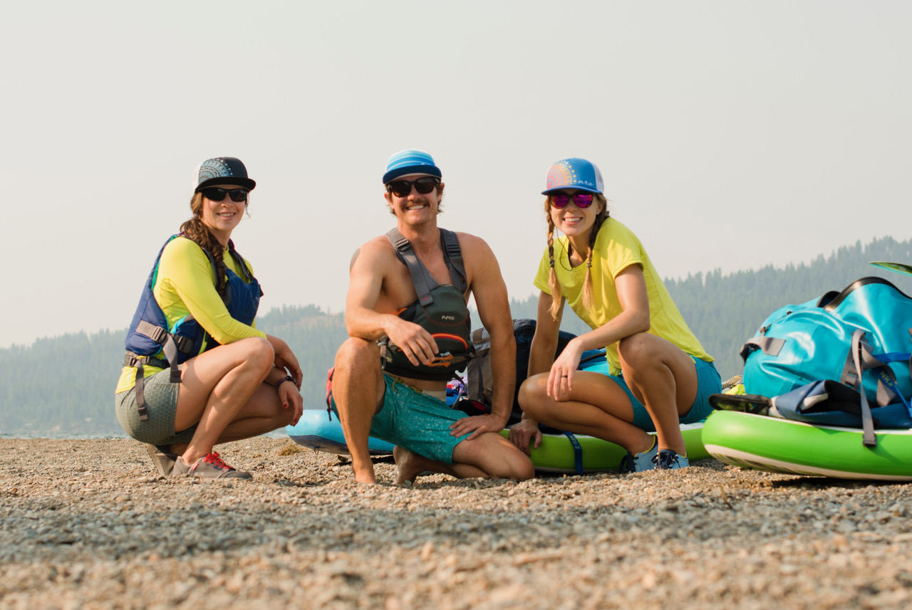 Grace, Jed, and Allie crouch near their paddle boards on land (Photo: Jed Conklin Photography)