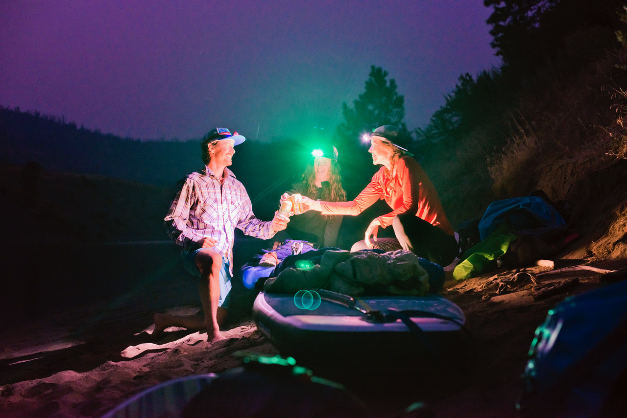 Paddle boarders "cheers" beers with head lamps and paddle boards on shore (Photo: Jed Conklin Photography)