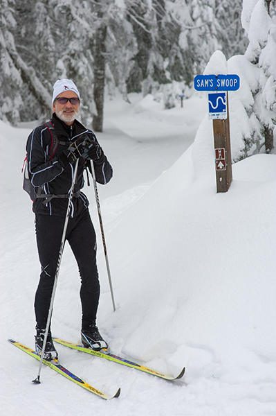 Photo of Sam Schlieder in front of trail sign for Sams Swoop.