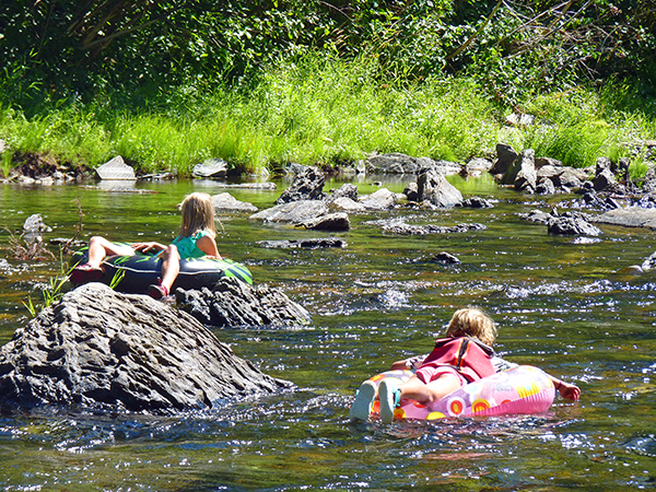 Photo of kids floating on tubes in a shallow part of the river.