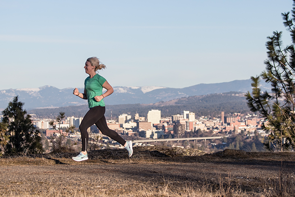 Photo of Kate Hellenthal running with Spokane skyline in the background.