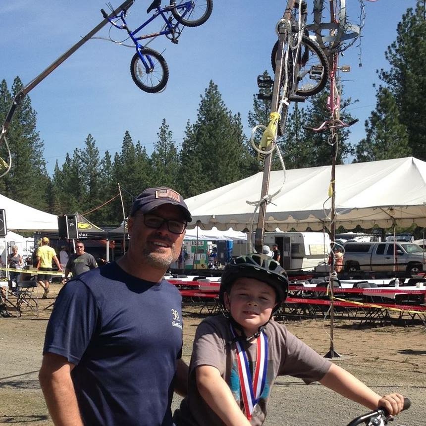 Father stands next to son on bicycle 