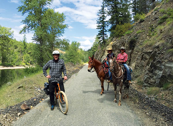 Photo of biker and two horses with riders stopped on the Ferry County Rail Trail.
