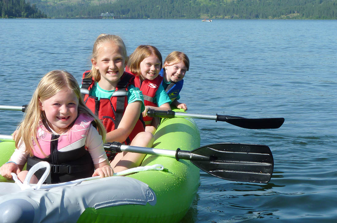 Photo of four kids in a kayak paddling on Lake Chatcolet in North Idaho.