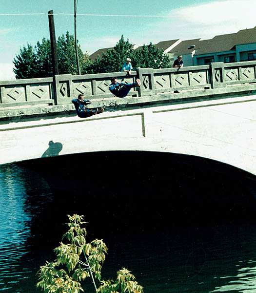 Photo of two waterskiers mid jump off of a bridge over the Spokane River.