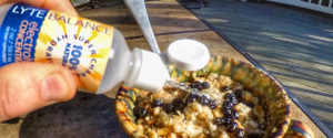 Photo of cup of oatmeal and person adding Lyte Balance Electrolytes to it.