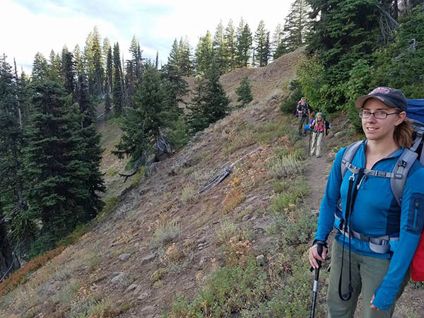 Photo fo hikers in foreground and background surrounded by Douglas Firs.