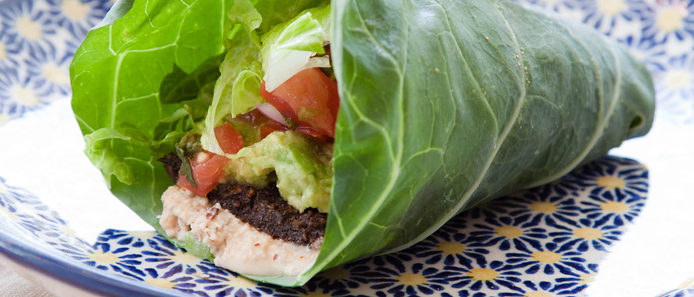 Photo of lettuce wrap with meat, guacamole, and vegetables.