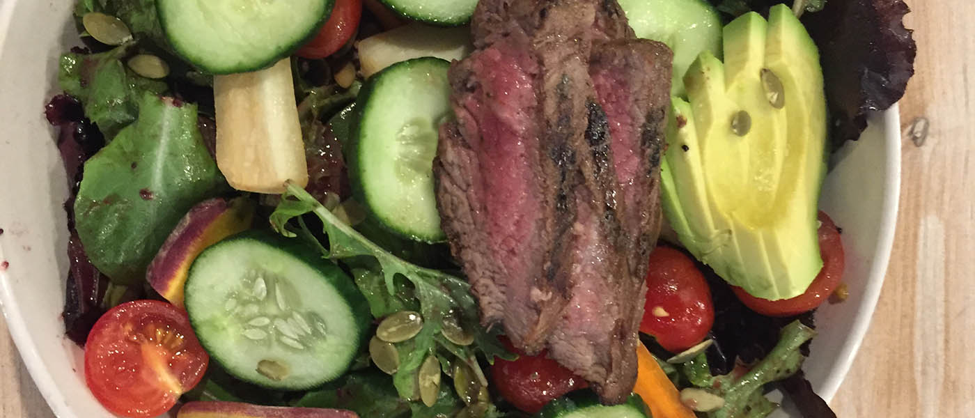 photo of salad with cucumbers, tomatoes, and steak.