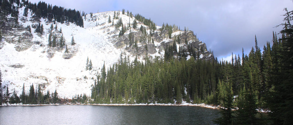 Photo of Lower Blossom lake with snow covered mountains in the background.