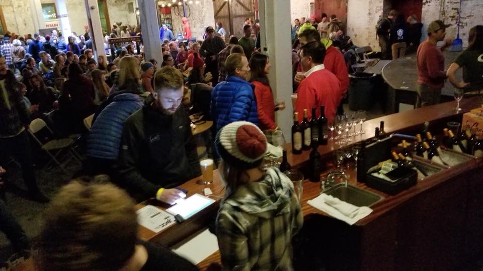 Man gets beer at a bar in room packed w people