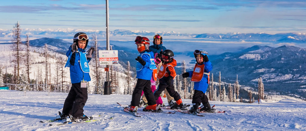 Photos of kids in a group ski lesson standing in front of a marked trail.