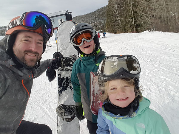 Selfie of Jason Graham with snowboard and two kids.