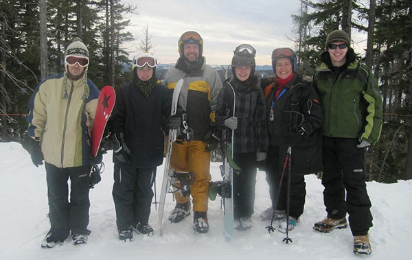 Photo of the Heston family posed on ski hill with skis and snowboards.