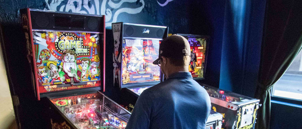 Photo of a man playing a Pinball arcade game at Berserk.