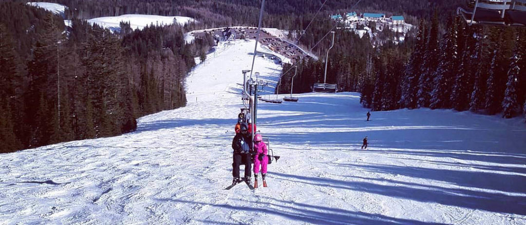 Photo taken from afar of father and daughter riding the chairlift at Mount Spokane.