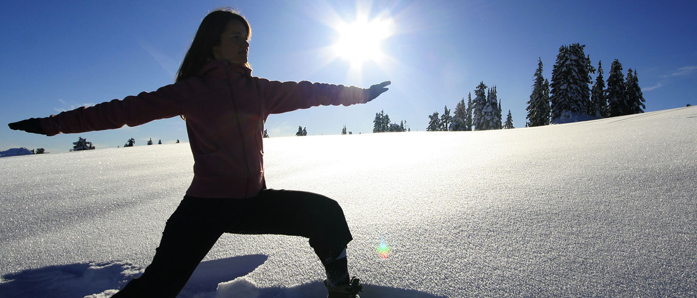 Photo of woman in yoga pose standing in untracked snow.