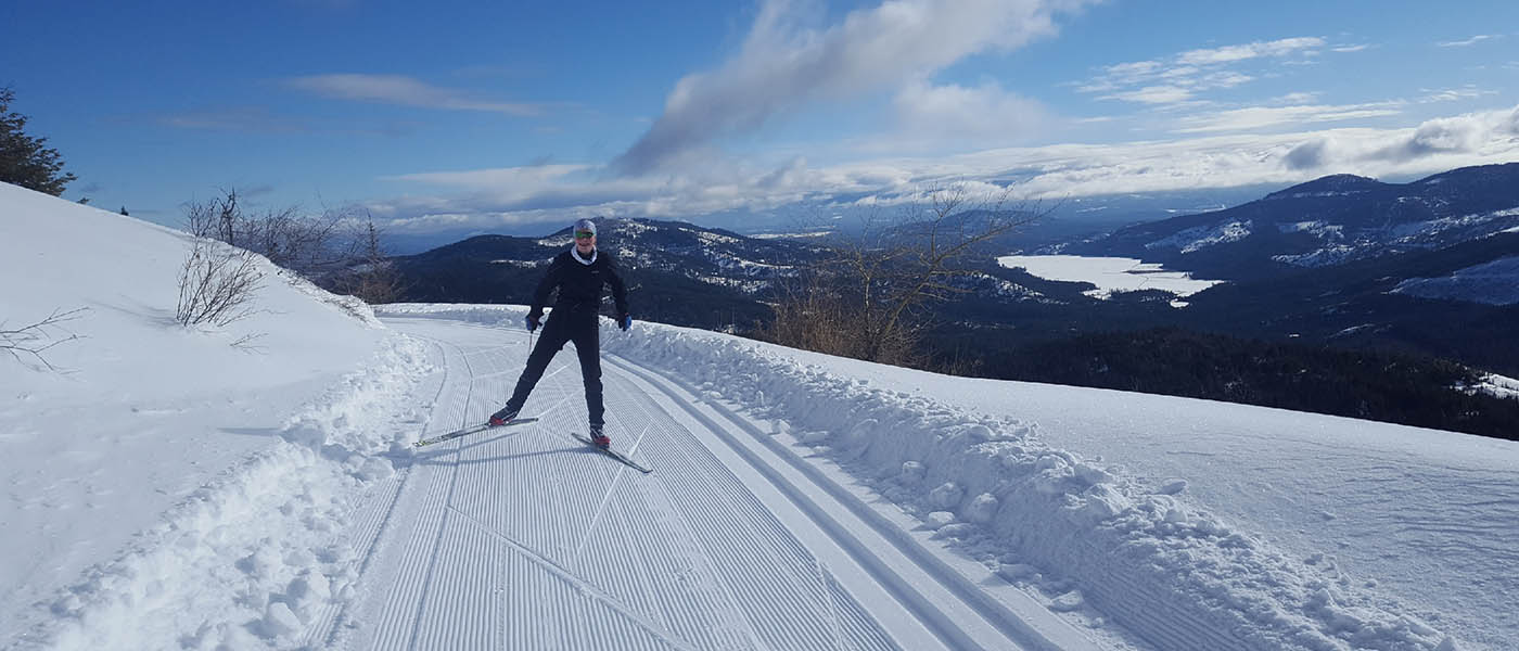 Photo of a man cross-country skiing with mountain peak in background.