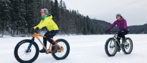 Photo of two girls fat biking on snow.