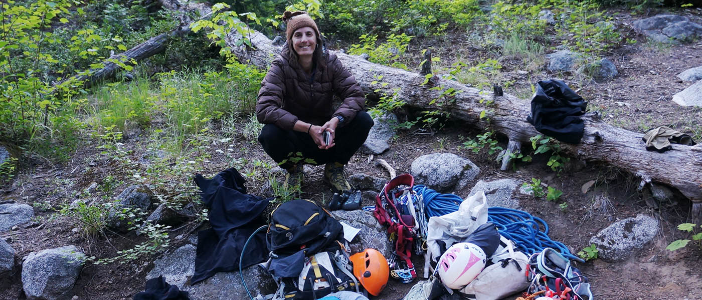Photo of the author in front of a pile of climbing gear laid out on the ground.