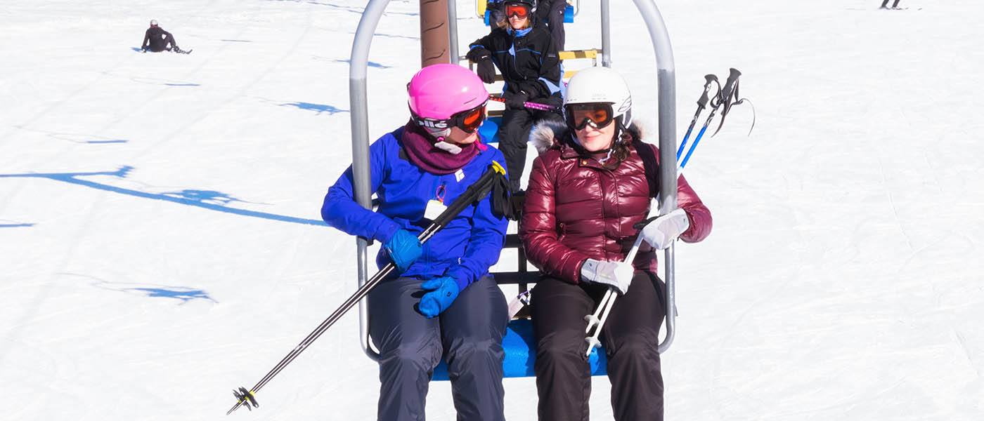 Photo of two female skiers riding the chairlift.
