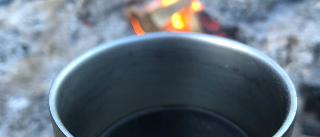 Photo of a camp mug in front of a fire.