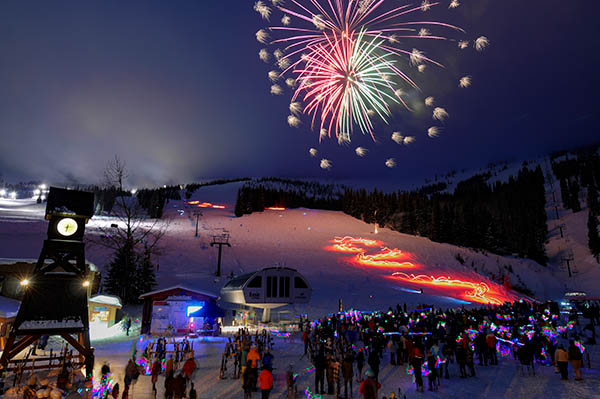 Photo of crowd looking at fireworks over ski hill.