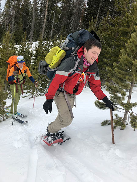 Photo of students snowshoeing through the trees.