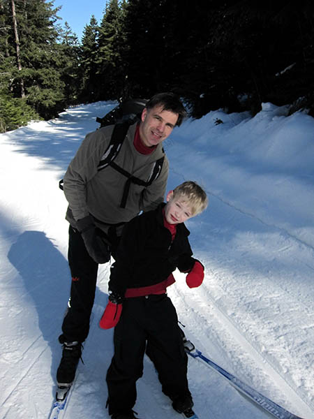 Photo of Trevin Hansen on nordic skis being supported by his father.