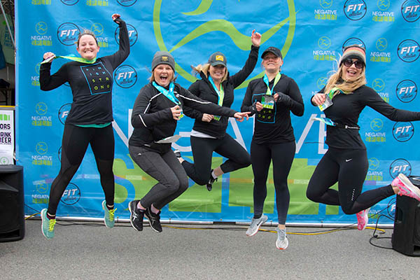 Photo of runners jumping in front of banner.