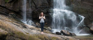 Photo of person practicing yoga in front of waterfall.