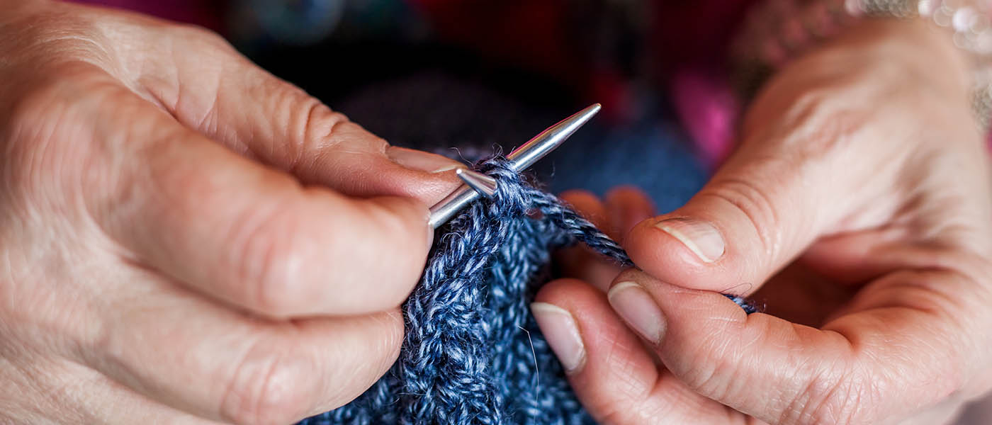 Close up photo of person knitting.