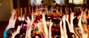 Photo of a group of people in a circle with arms raised.