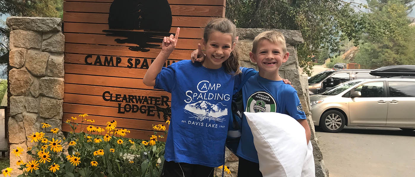 Photo of siblings in front of Camp Spalding sign