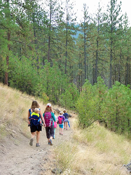 Photo of kids and parents hiking along single track hiking trail.