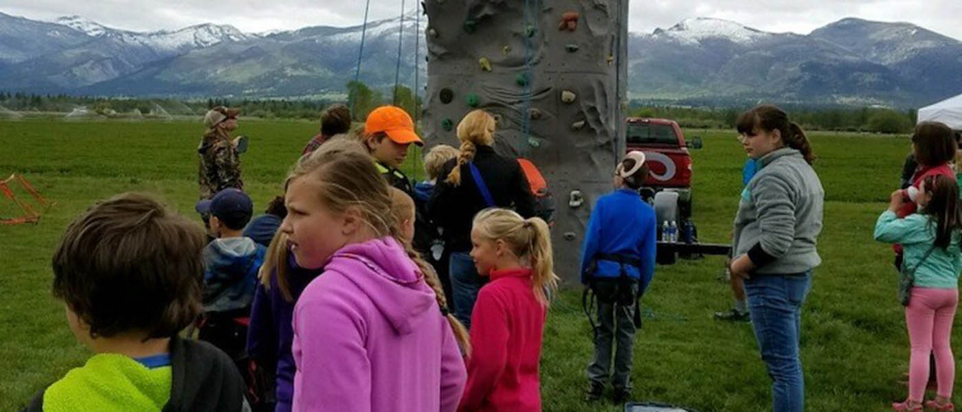 Photo of kids standing around a fiberglass rock wall.