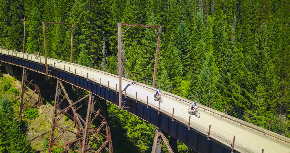 Bikers pedaling along a high trestle bridge on the Route the Hiawatha in North Idaho.