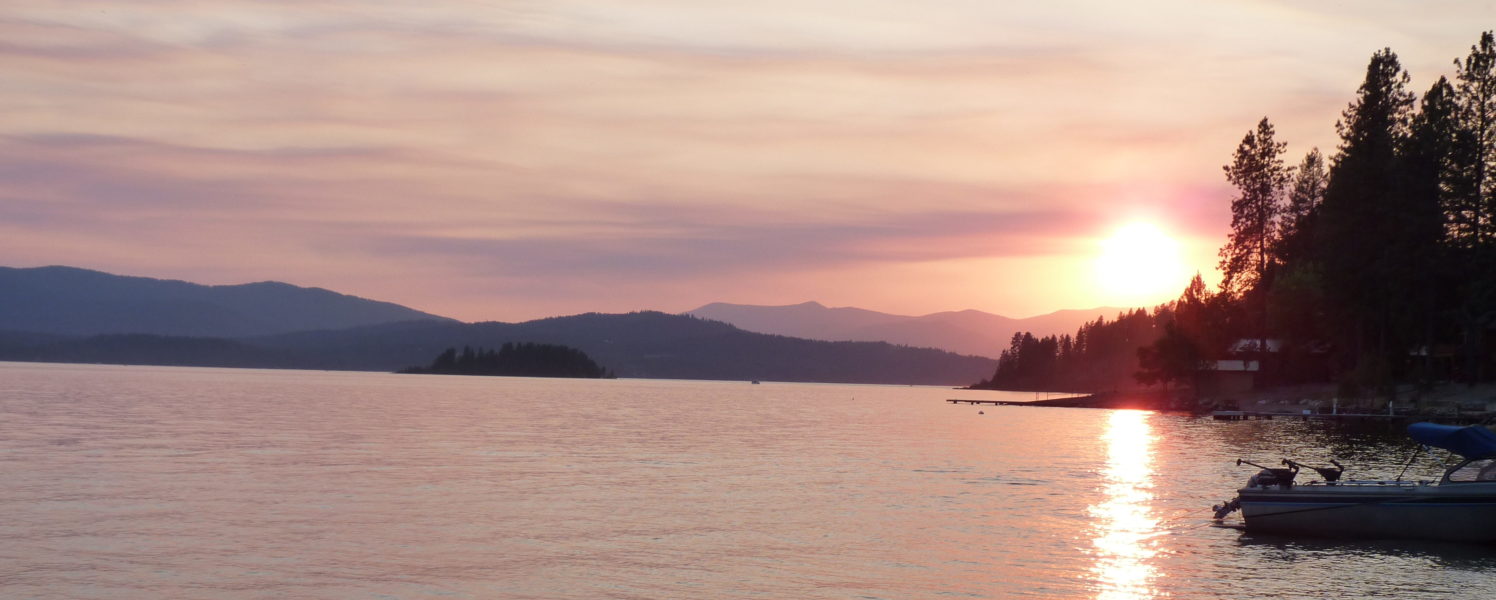 Sunset at Lake Pend Oreille, with rich hues of pink, yellow, and orange in the sky.