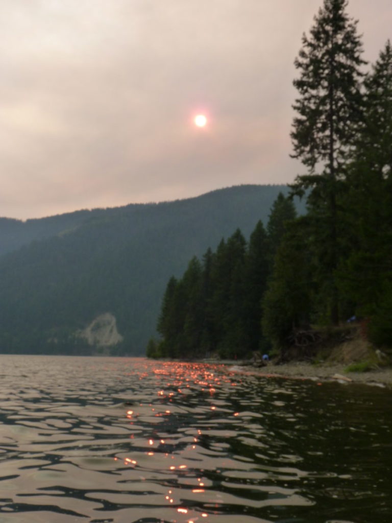 Wildfire smoke at Sullivan Lake obscures the sun, making it appear pink.
