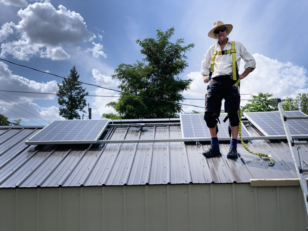 Eco Depot owner and solar installer standing on a roof with solar panels.