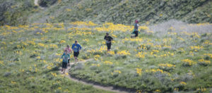 A group of people running on a hill trail.