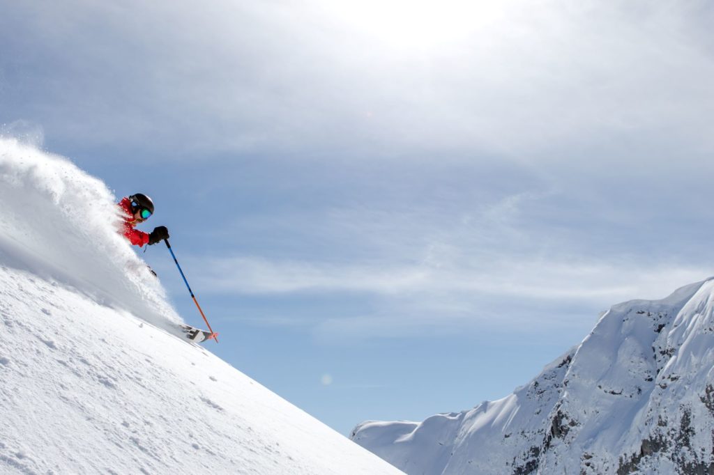 Skier going down a steep and deep powder run