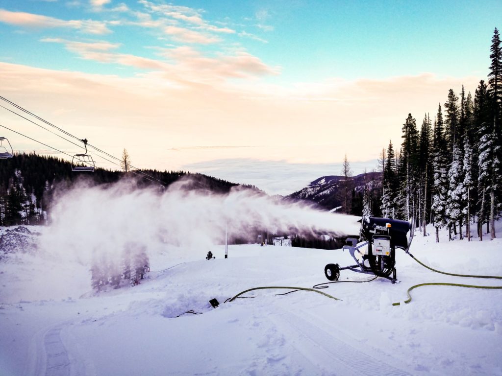 Snow-blowing machine shooting out new snow on a ski run.