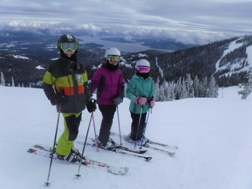 A group of kid skiers on top of a mountain.